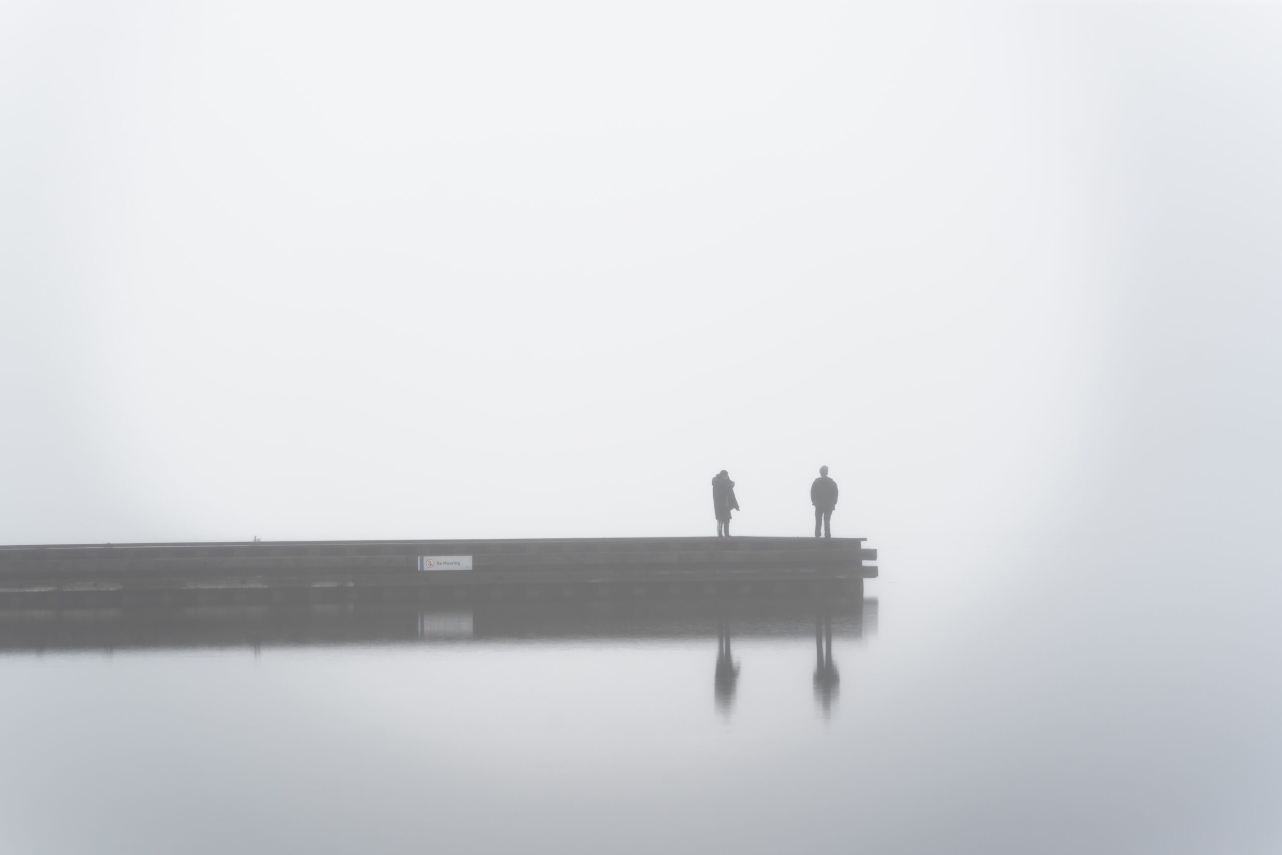 Two,people,on,a,dock,in,thick,fog,at,beach
